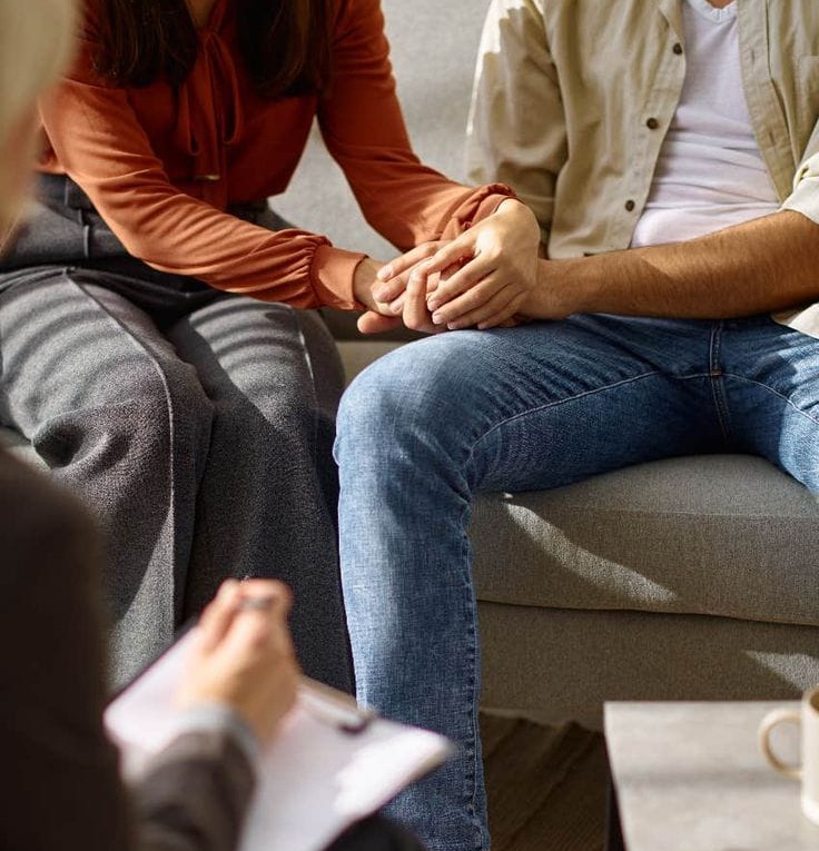 A couple sitting close together, engaged in a supportive conversation